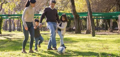 A family plays soccer together in a sunny park, enjoying quality time outdoors.