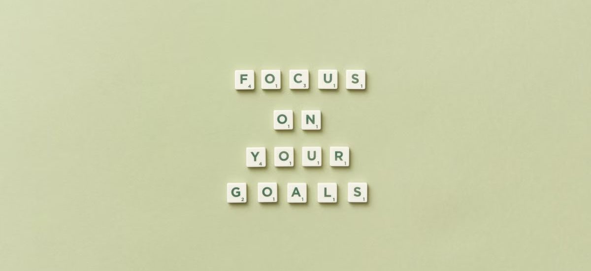 Scrabble letters forming a motivational phrase 'Focus on Your Goals' on a light green background.