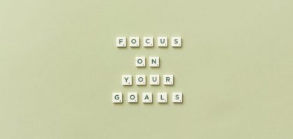 Scrabble letters forming a motivational phrase 'Focus on Your Goals' on a light green background.