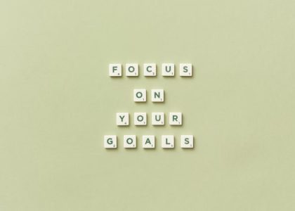 Scrabble letters forming a motivational phrase 'Focus on Your Goals' on a light green background.