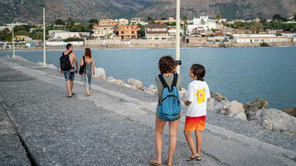 Two children stand on a pier looking out at the water